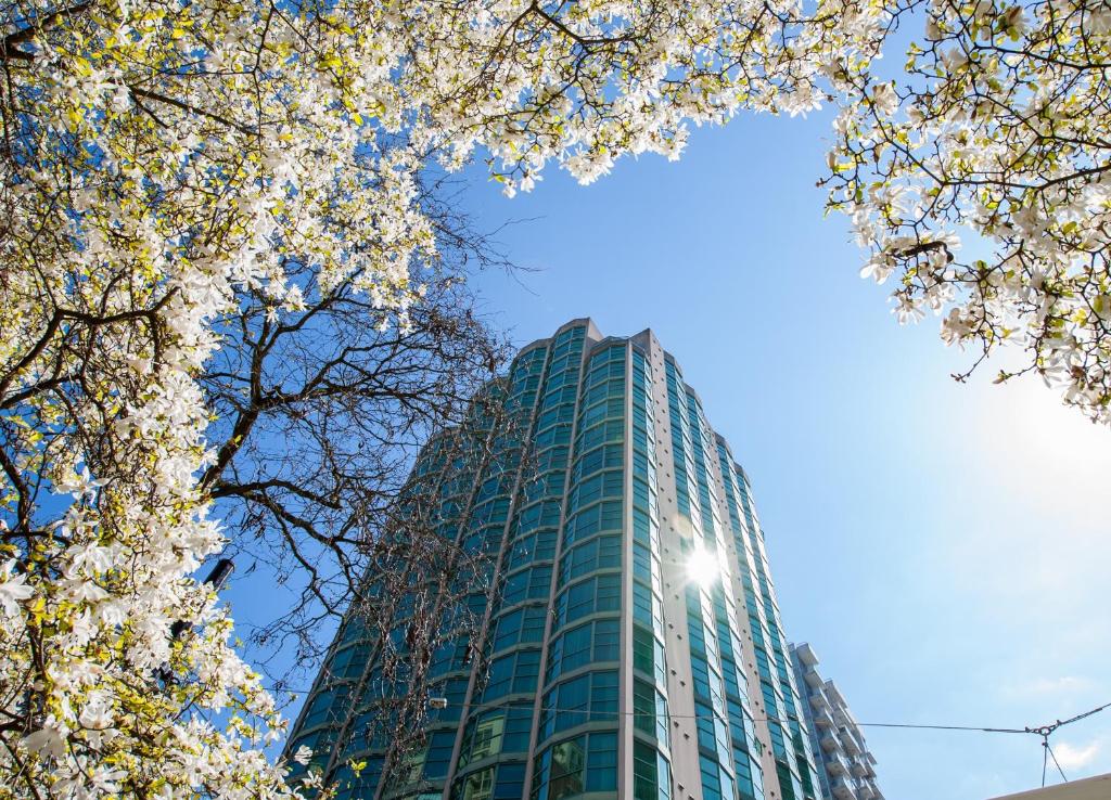 ein hohes Gebäude mit weißen Blumen davor in der Unterkunft Rosedale on Robson Suite Hotel in Vancouver