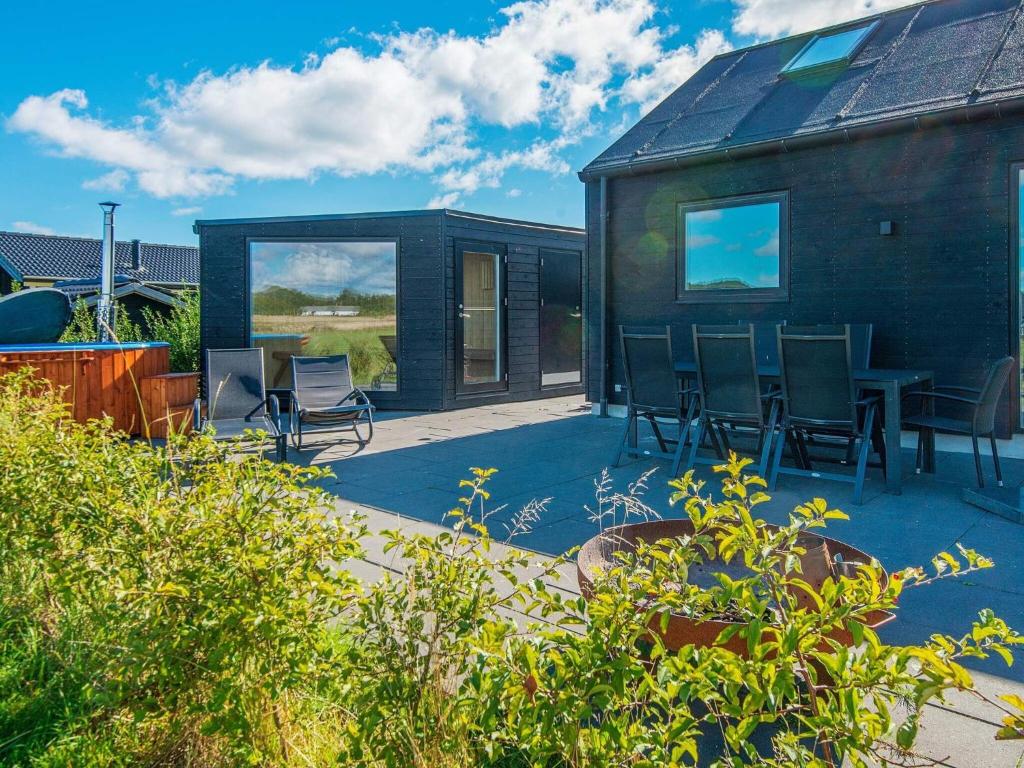 ein schwarzes Haus mit Stühlen und einem Tisch auf einer Terrasse in der Unterkunft 10 person holiday home in Odder in Odder