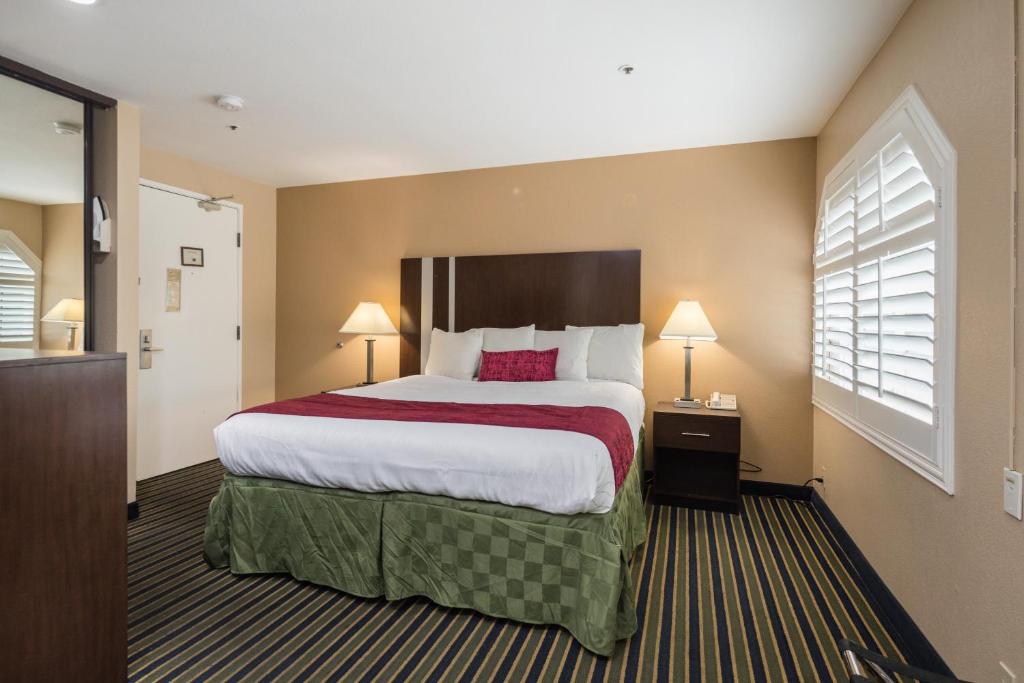 ein Hotelzimmer mit einem großen Bett und zwei Lampen in der Unterkunft Travel Inn Sunnyvale in Sunnyvale