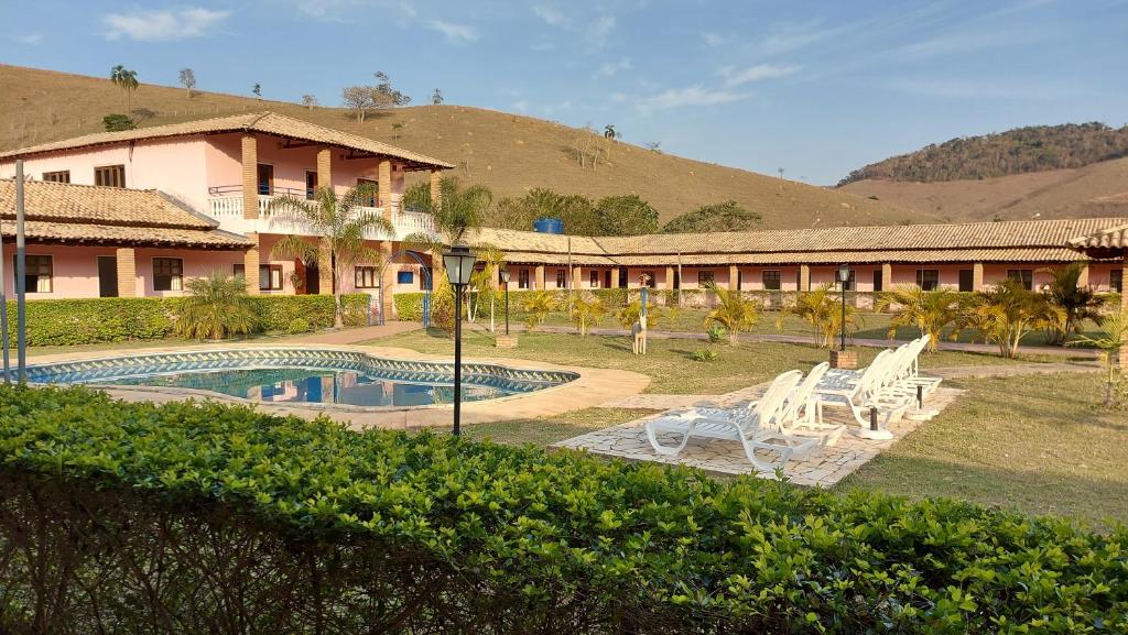 a resort with a pool and chairs and a building at Pousada Recanto Nativa's in São Luiz do Paraitinga