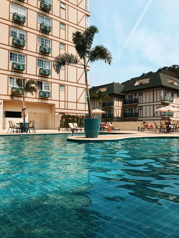 a swimming pool in front of a large building at Live Suites Itaipava in Itaipava