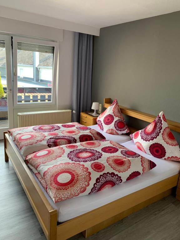 een slaapkamer met een bed met rode en witte dekens en kussens bij vina am ring in Mannebach