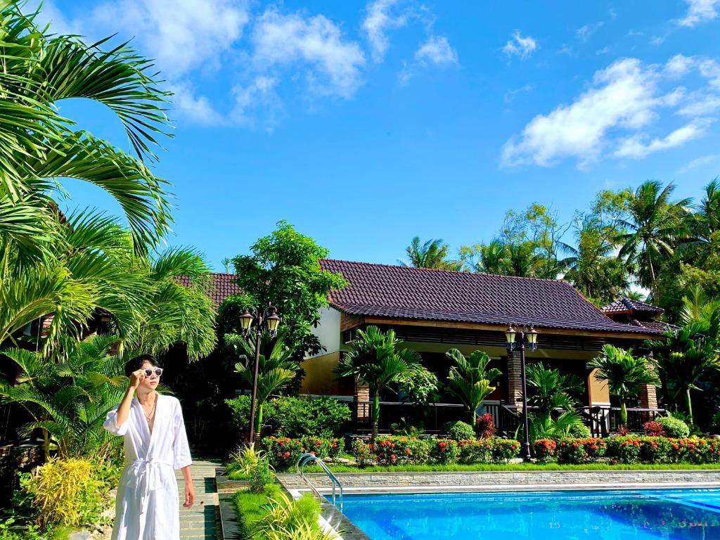 a woman talking on a cell phone in front of a pool at Qualia Resort Phu Quoc in Phú Quốc