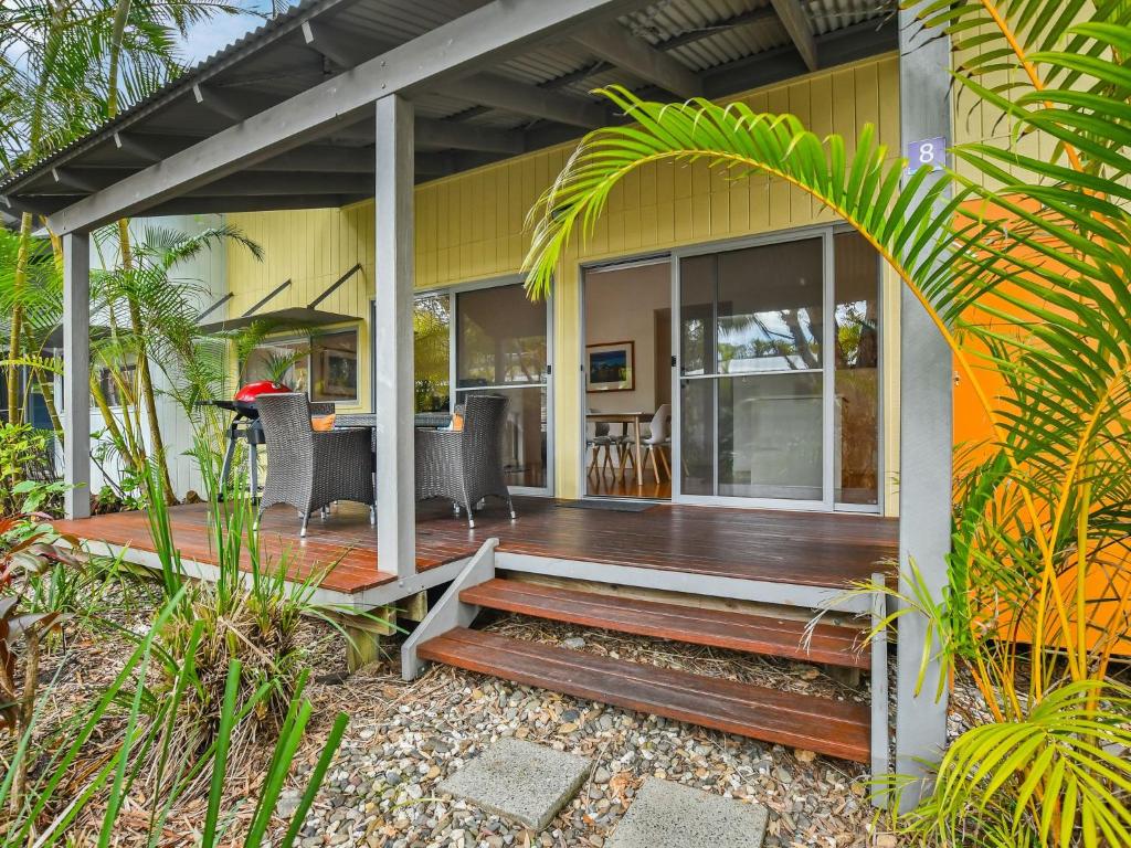 a house with a wooden deck with a table and chairs at Mobys Resort 08 in Boomerang Beach