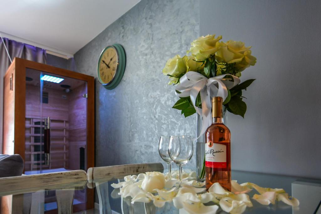 eine Flasche Wein und eine Vase Blumen auf dem Tisch in der Unterkunft Apartamenty hoteLOVE z sauną przy Strumieniu in Karpacz