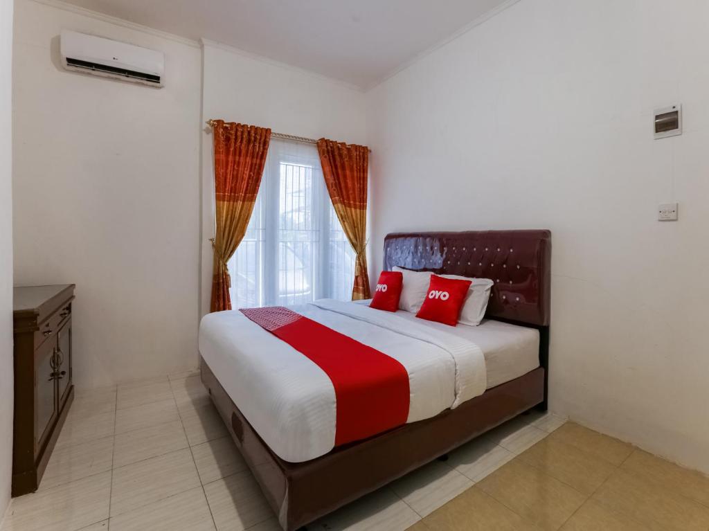 um quarto com uma cama com almofadas vermelhas e uma janela em OYO 3907 Mine Residence em Padang