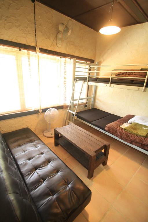 a room with a bunk bed and a couch and a bench at Taketomijima Guesthouse and je Taime in Taketomi