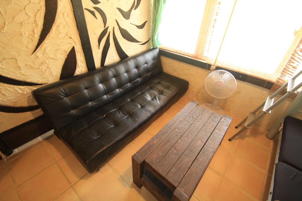 a leather couch in a living room with a table at Taketomijima Guesthouse and je Taime in Taketomi