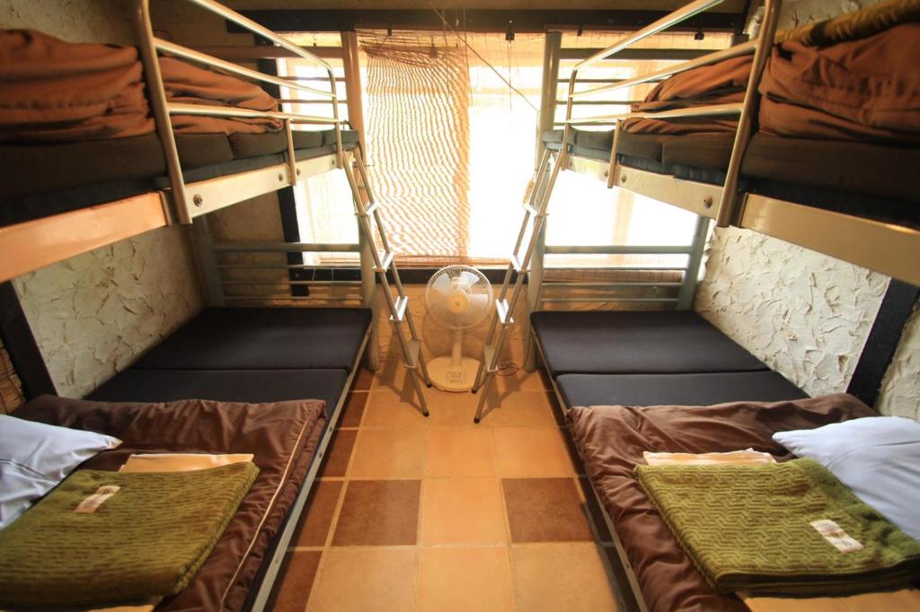 a room with two bunk beds and a fan at Taketomijima Guesthouse and je Taime in Taketomi