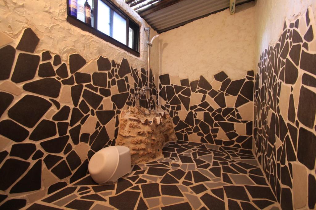 a bathroom with black and white tiles on the wall at Taketomijima Guesthouse and je Taime in Taketomi