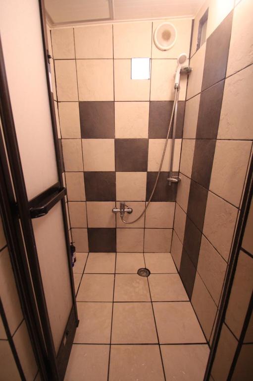 a bathroom with a shower with black and white tiles at Taketomijima Guesthouse and je Taime in Taketomi