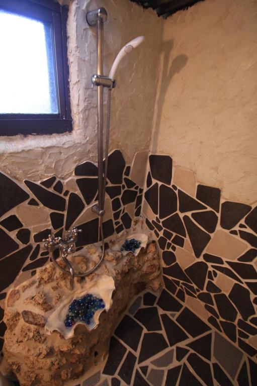 a shower in a bathroom with a stone wall at Taketomijima Guesthouse and je Taime in Taketomi