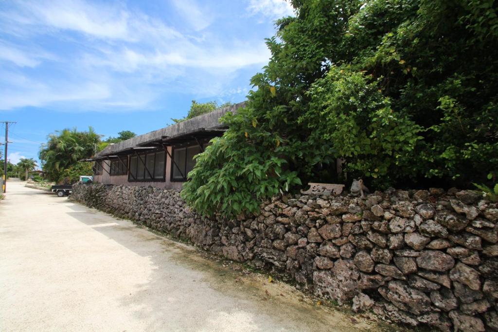 a stone retaining wall next to a building at Taketomijima Guesthouse and je Taime in Taketomi
