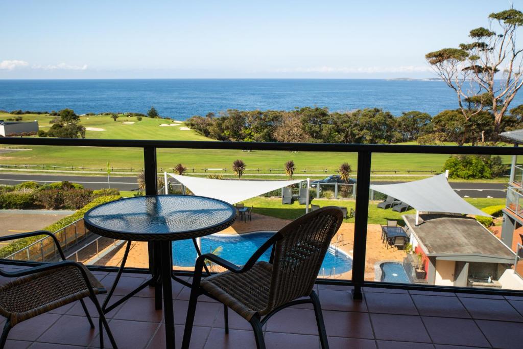 balcón con mesa, sillas y vistas al océano en Amooran Oceanside Apartments and Motel, en Narooma