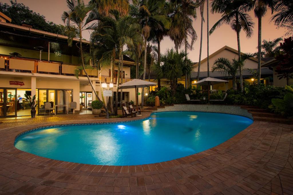 a large blue swimming pool in front of a building at Tamboti Lodge Guest House in Tzaneen