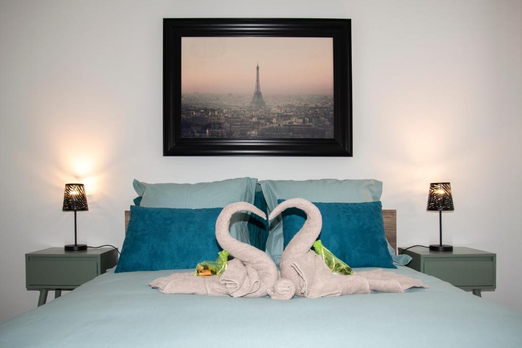 two swans are making a heart shape on a bed at La Clé des Expos "In Paris" 2 in Arcueil