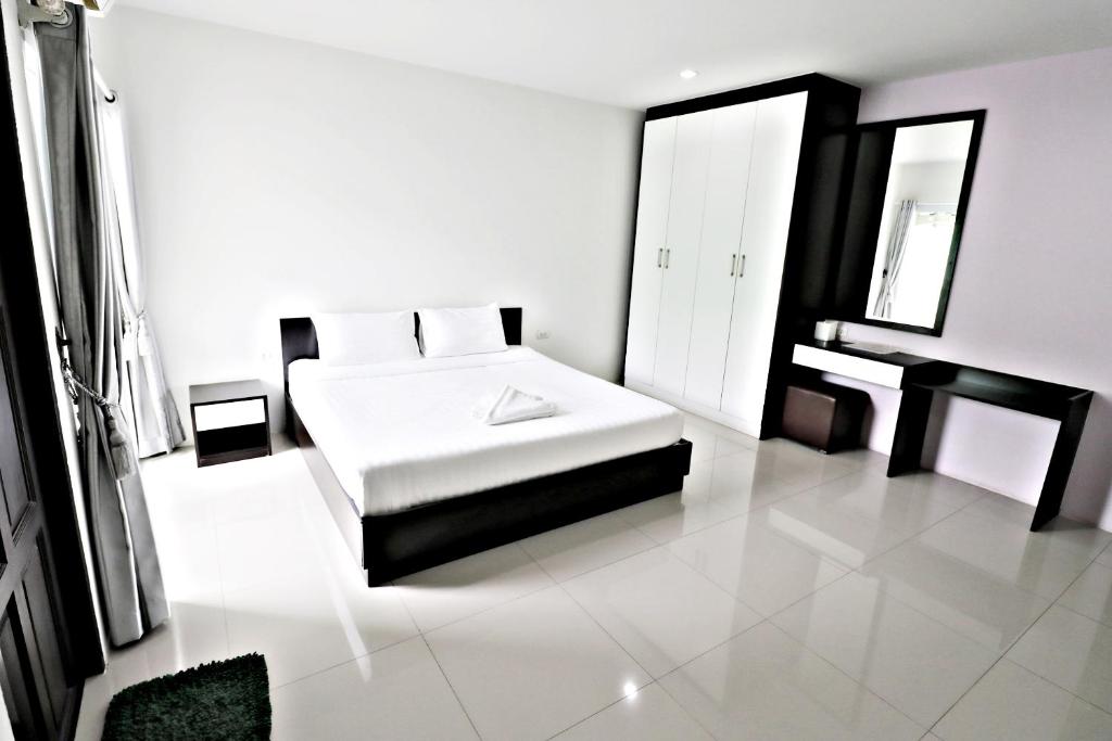 Habitación blanca con cama y espejo en Hua Hin Irooms, en Hua Hin