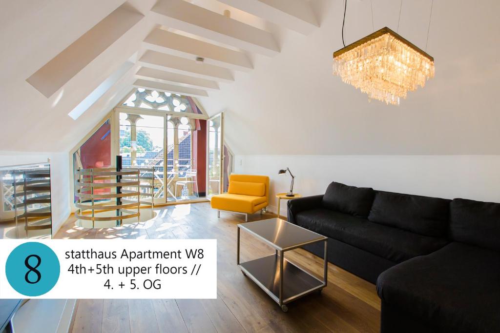 - un salon avec un canapé noir et un fauteuil jaune dans l'établissement statthaus - statt hotel, à Cologne
