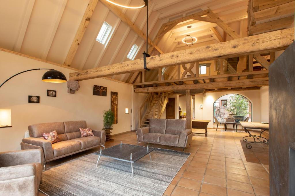 a living room with wooden ceilings and couches and a table at LA TOUR des fées-spa in Mittelbergheim