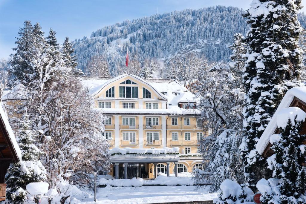 a large building in the snow with snow covered trees at Le Grand Bellevue in Gstaad