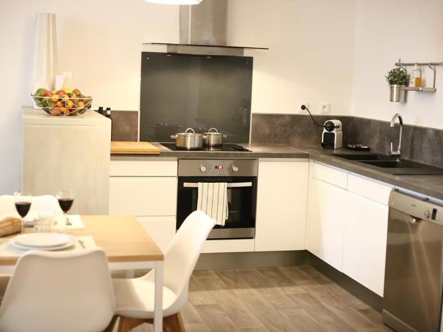 a kitchen with white cabinets and a table and a stove at Maison Bacou Cité 3 in Carcassonne
