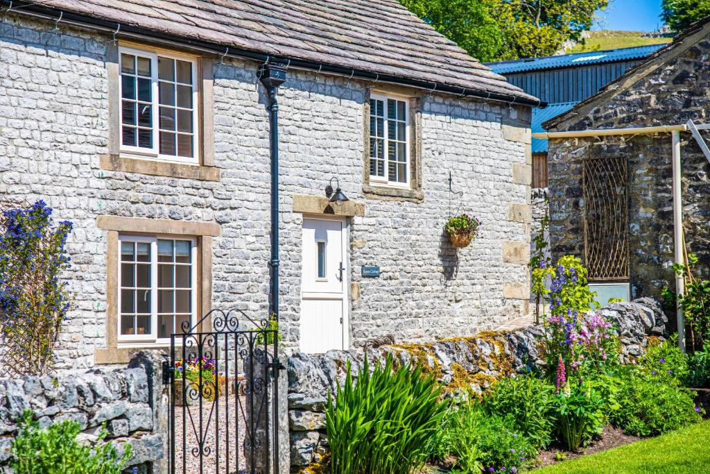 a stone cottage with a white door and a stone wall at James Cottage in Chelmorton