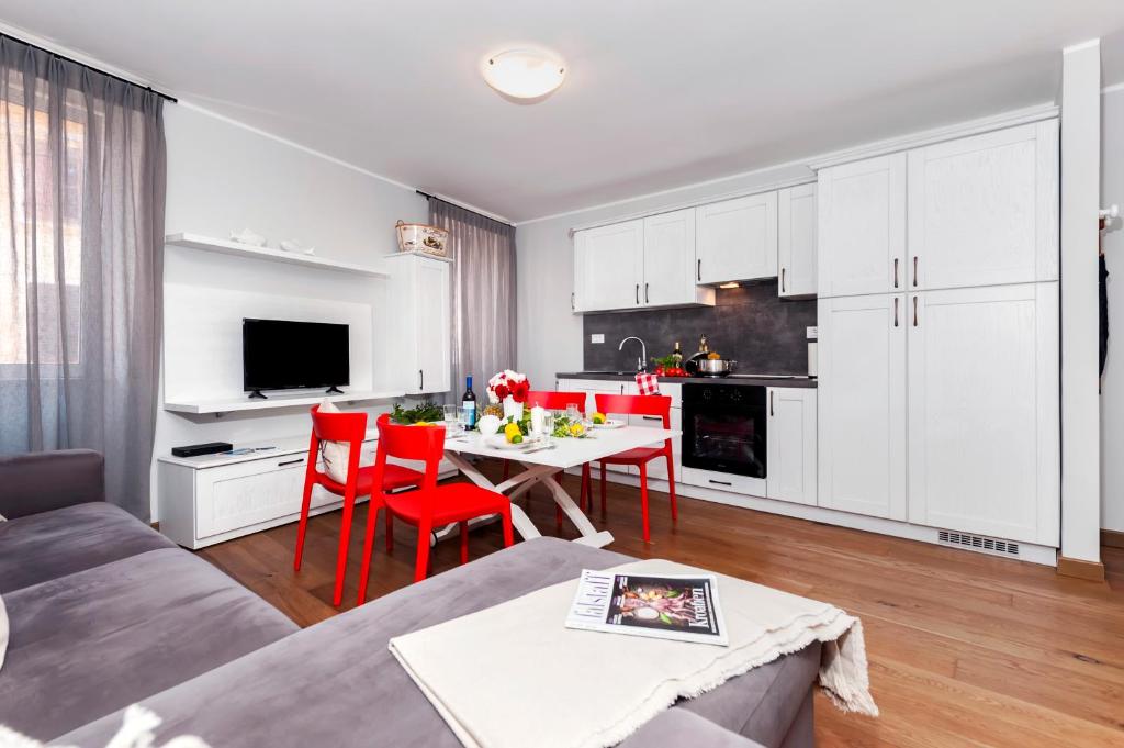 a kitchen and living room with a table and red chairs at Nel Centro City Apartment in Rovinj