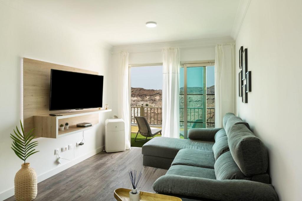 uma sala de estar com um sofá e uma televisão de ecrã plano em Apartamento Happy Dreamer em Puerto Rico de Gran Canaria
