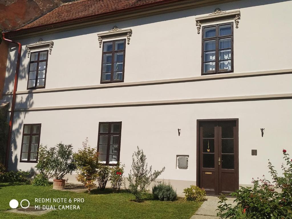 een wit huis met zwarte ramen en een deur bij Centrum Szíve in Pécs
