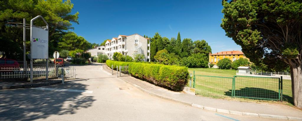 a street with a fence and a building and trees at Hotel Flores in Poreč