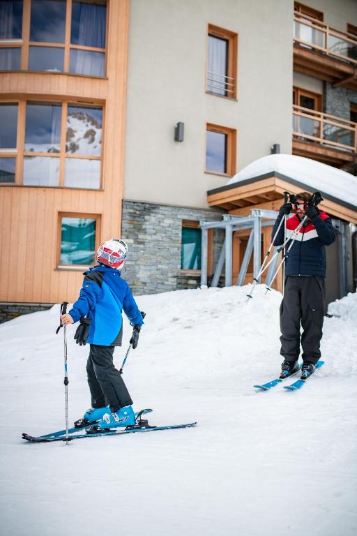 two people on skis in the snow in front of a building at Le Taos in Tignes