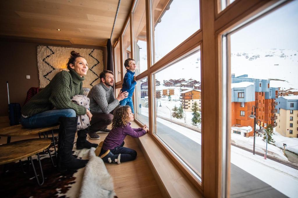 a family sitting in a room looking out of a window at Le Taos in Tignes
