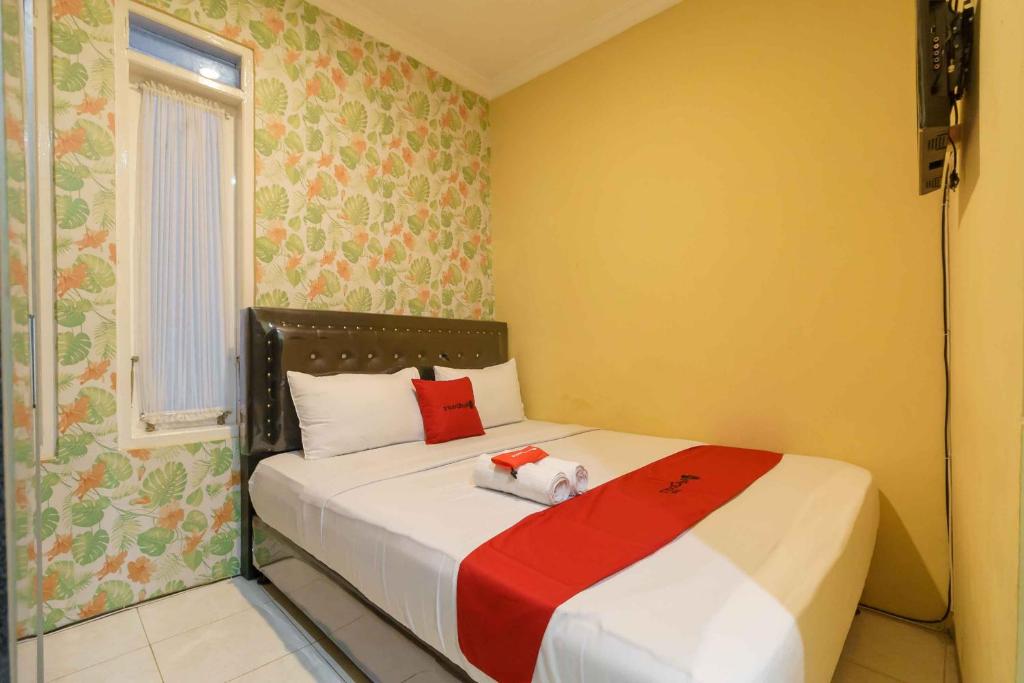 a small bedroom with a bed with a red blanket at RedDoorz Syariah near Jam Gadang Bukittinggi 2 in Bukittinggi
