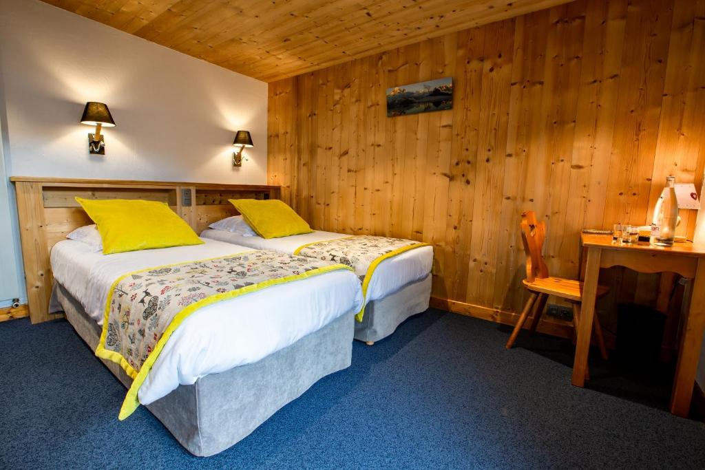a bedroom with two beds and a wooden wall at Hotel Les Bruyères in Morzine