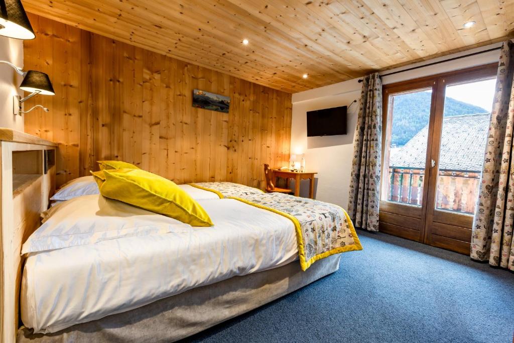 a bedroom with a bed and a large window at Hotel Les Bruyères in Morzine