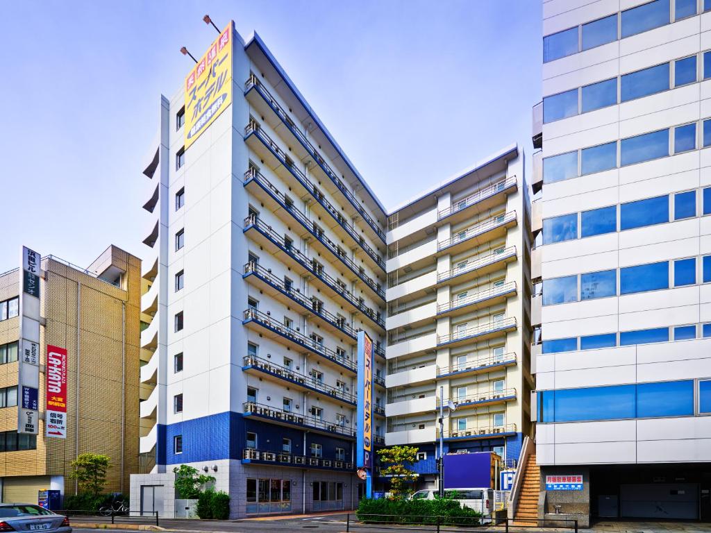 un edificio alto de color blanco con ventanas azules en Super Hotel Saitama Omiya West, en Saitama