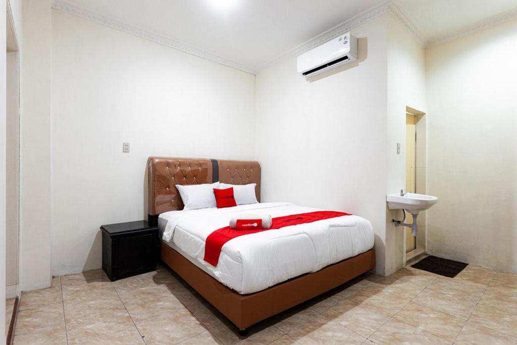 a bedroom with a large bed and a sink at RedDoorz near Yuki Simpang Raya Mall Medan 2 in Medan