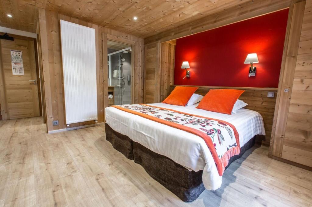 a bedroom with a large bed with a red wall at Hotel Les Bruyères in Morzine