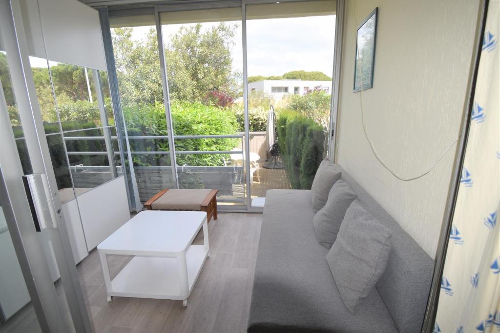ein Wohnzimmer mit einem Sofa und einem großen Fenster in der Unterkunft les jardins du port studio avec jardin et piscine in Le Grau-du-Roi