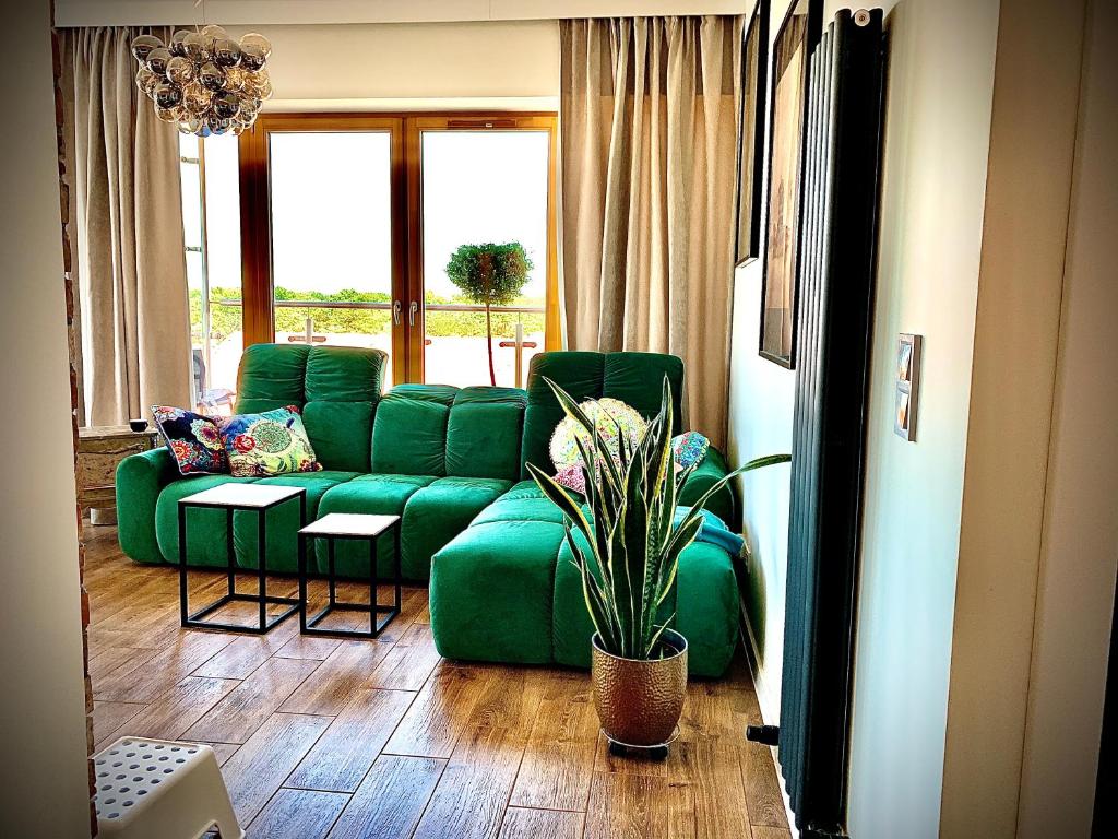 a living room with a green couch and a potted plant at Apartament Suite Tower in Świnoujście