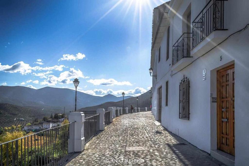 uma rua de calçada ao lado de um edifício com o sol em La casa del Mejorato em Priego de Córdoba