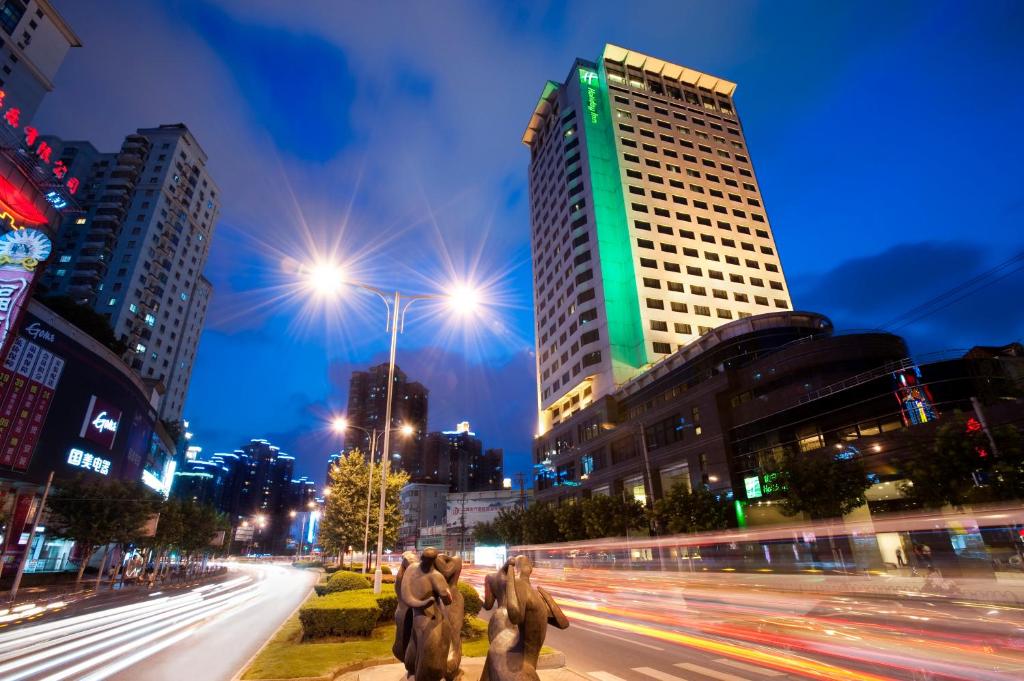 een groep mensen die 's nachts door een straat lopen bij Holiday Inn Shanghai Vista, an IHG Hotel in Shanghai