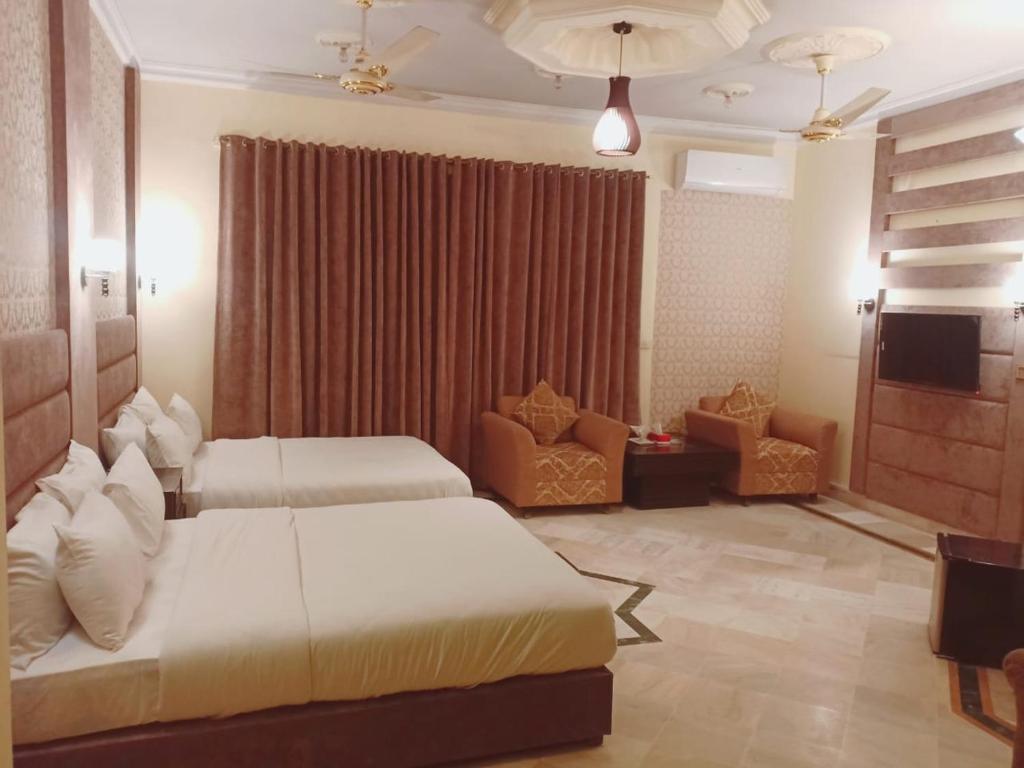 a hotel room with two beds and a television at Casa Grande in Islamabad