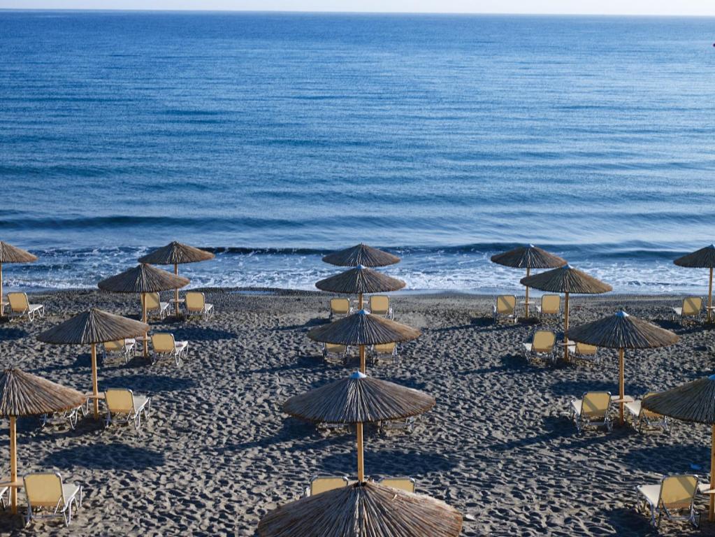a group of umbrellas and chairs on a beach at Atlantica Akti Zeus Hotel in Amoudara Herakliou