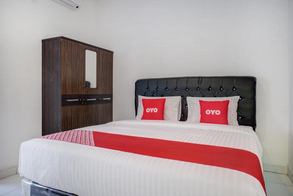 a bedroom with a large bed with two red pillows at OYO 3690 Wisma Yani Syariah in Padang