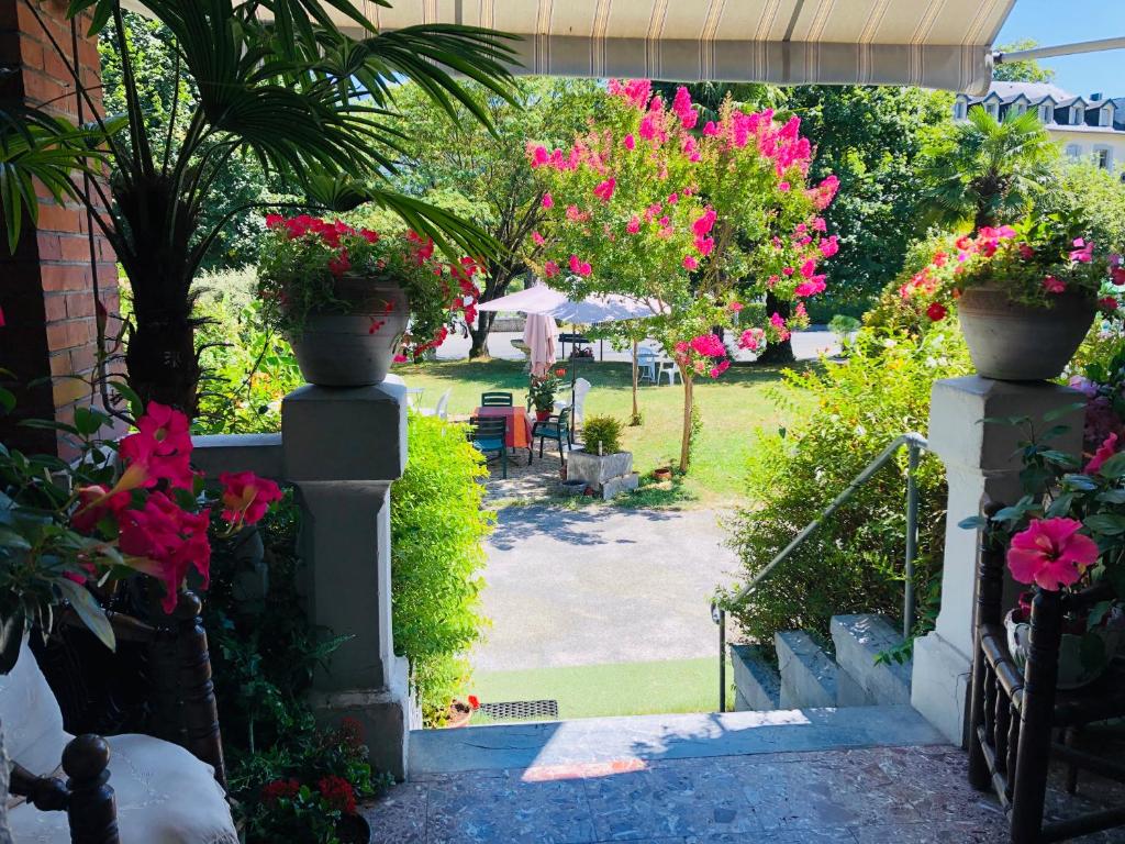 een toegang tot een tuin met roze bloemen en planten bij Studio dans Villa historique "Victoria" in Argelès-Gazost
