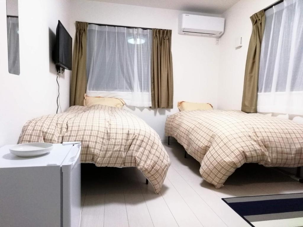 クレアゲハウス新百合ケ丘 في كاواساكي: غرفة نوم بسريرين وتلفزيون فيها