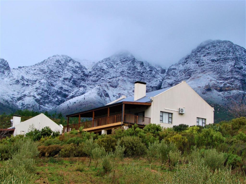 a house on a hill with mountains in the background at Vredehoek Guest Farm in Breerivier