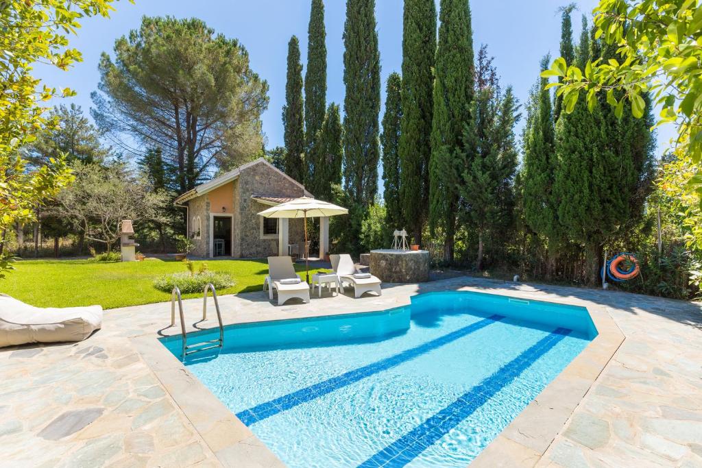 einen Pool in einem Garten mit zwei Stühlen und einem Sonnenschirm in der Unterkunft Petrinos Cottage in Dafnila