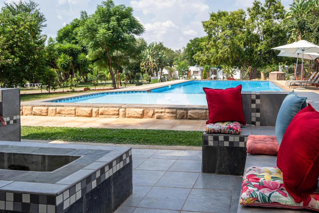 a bench with red pillows next to a swimming pool at Graceland Conference and Lifestyle Centre in Hartbeespoort